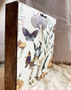 The back is finished with a charming vintage wallpaper and includes an attached hanger for easy hanging.