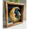 Angled view of Dreamy highlighting the dimensional clay moon and mushroom sculpture, handcrafted details, and depth of the handmade wooden frame.
