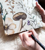 Back view of the Tranquil sculpture featuring the decorative mushroom-patterned wallpaper, wall hanger, and artist Cheryl Baker’s signature.