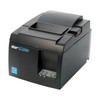 A product shot from the file star-micronics-tsp143iiibi-bluetooth-thermal-receipt-printer-gray-39472110-side.jpg displaying a dark gray Star Micronics TSP100III POS printer from an elevated side angle. The image highlights the printer's rectangular profile, top-loading paper lid, receipt exit slot, front-facing logos, and a small rectangular access panel on the left lower side.