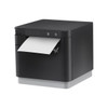 Three-quarter angle view of the Star mC-Print3 (mCP30) thermal receipt printer in matte black with a light gray base. A length of white thermal receipt paper is shown emerging from the top exit slot, highlighting the printer's compact, cube-like design and front-facing control interface.