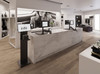 A modern retail clothing boutique checkout counter featuring multiple POS checkout stations equipped with touchscreen monitors, receipt printers, and payment terminals mounted on ergonomic adjustable arms.