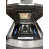 An overhead view looking inside an open Datalogic Magellan 9800i series scanner scale housing with the top platter lifted, revealing the internal mirror arrays, dual blue glass-securing tabs, and the manufacturer model label printed with Magellan 9800i.
