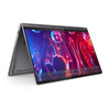 A dark gray Lenovo Yoga 9i 2-in-1 laptop, with the screen and keyboard sections folded into a tent shape on a white surface. The screen displays a video of a concert with people's hands raised in red and blue lighting, and playback controls are visible at the bottom of the display.