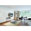 A modern living room with a white wall mounted television displaying a beach scene using the Peerless-AV PA740 articulating wall mount above a linear fireplace, with a glass coffee table, armchairs, and floor-to-ceiling windows.