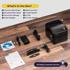 Package contents for the Volcora label printer laid out on wood flooring, showing the printer, power adapter, USB cable, driver CD, instruction manual, 1-inch label spindle, fix tabs, and 1.5-inch core adapters.