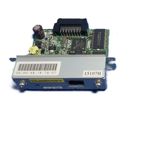 A front-angled view of a green Epson interface circuit board, highlighting the external connection port. A silver metal faceplate features an Ethernet (RJ45) port, two mounting screws, and a sticker with a barcode and MAC address. Behind the faceplate, the circuit board is visible with various electronic components, including integrated circuits and capacitors, ending in a black multi-pin internal connector at the top.