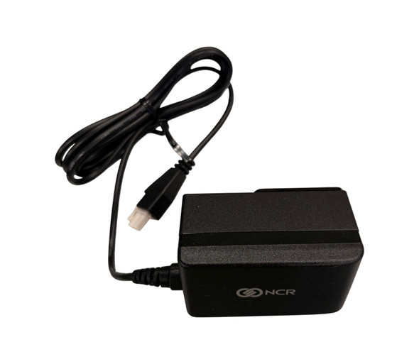 A top-down perspective view of a black NCR AC power adapter on a white background. The rectangular power brick features the silver NCR logo on its side. A black power cable is attached to the left side of the brick, which is coiled and secured at the top. The cable ends in a white 2-pin female connector, similar to those used for Point of Sale (POS) equipment.