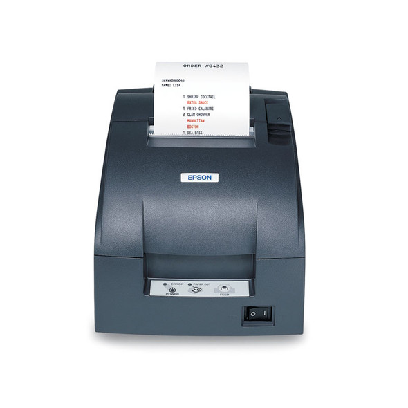 A high-resolution product photograph of the front of a dark gray Epson impact kitchen printer against a plain white background. The device features a robust, industrial design. At the top, a food order receipt emerges from the slot, clearly showing the red ink modifications. The control panel at the bottom includes status LEDs (power, error, paper out), a large feed button, and a prominent mechanical rocker power switch.