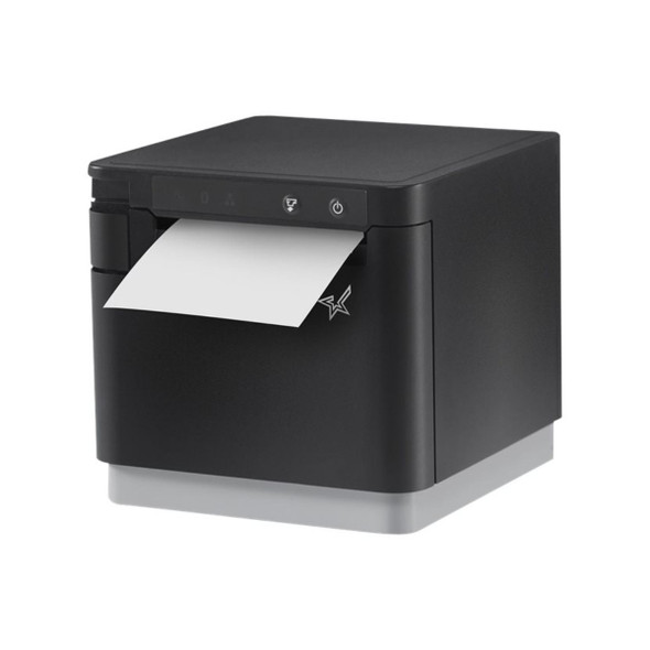 Three-quarter angle view of the Star mC-Print3 (mCP30) thermal receipt printer in matte black with a light gray base. A length of white thermal receipt paper is shown emerging from the top exit slot, highlighting the printer's compact, cube-like design and front-facing control interface.