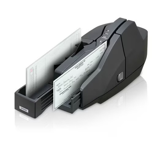 An angled side view of the dark grey Epson CaptureOne TM-S1000 check scanner, showing the paper input tray on the left loaded with multiple checks and one check actively feeding through the scanning path. LED status lights are visible on the top interface panel.