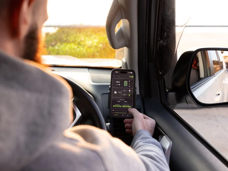 Driver checking REDARC RedVision app showing 99% battery charge while on the road