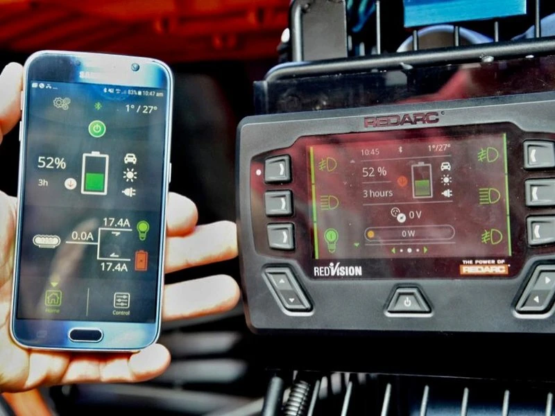REDARC RedVision in-vehicle display and smartphone app side by side, both showing battery status and controls