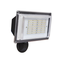 42W Outdoor LED Wall Pack Light in Bronze finish mounted on exterior wall.  LED wall pack light illuminating a parking lot at night.