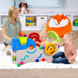Toddlers playing with steering wheel and balls in baby activity center 