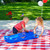 little boy and girl playing with the red white and blue America 250 double sided track table on a plaid picnic blanket