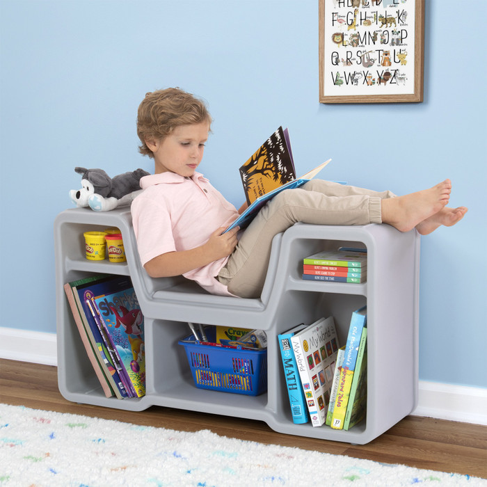 Boy lounging on cozy cubby reading nook enjoying a book.