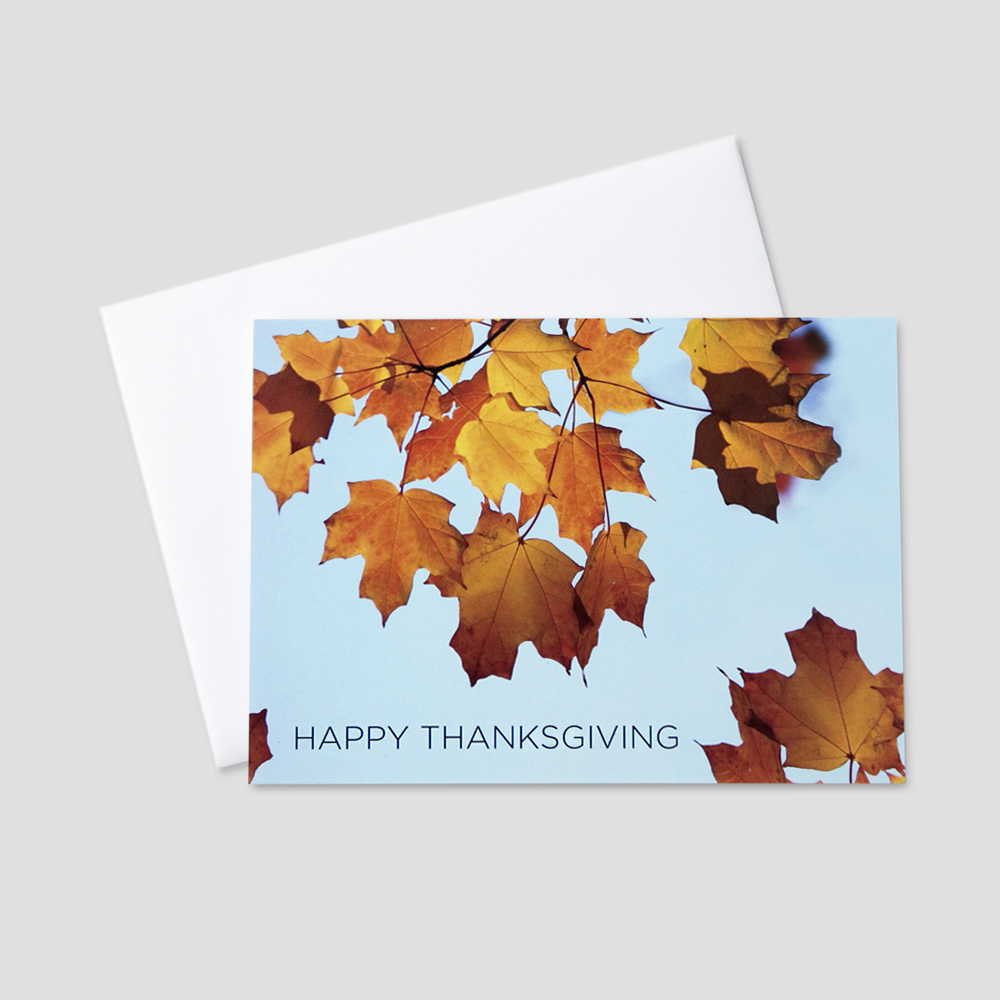 Client Thanksgiving greeting card with a blue sky and autumn leaves on a tree and Happy Thanksgiving in a block font
