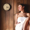 Image of woman sitting next to Handcrafted Sleek Analog Clock in Finnish Pine Wood in a sauna.