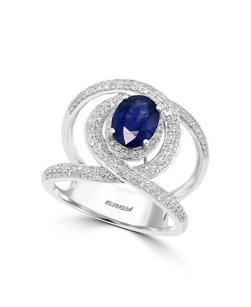 The sapphire ring standing upright and perfectly centered on a seamless, glossy white (#FFFFFF) background, capturing the deep blue stone reflecting directly down onto the surface.