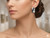 Sophisticated model wearing a single Éclat X diamond crossover earring for a high-end jewelry editorial look, elegant and chic