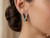 Side profile of criss-cross earrings showing the secure hinge closure and polished 14K white goldfinish.