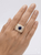 Top-down view of a 2-carat diamond and sapphire dome ring on a white background.