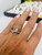 Model hand A beautiful horizontal banner image featuring the ring resting on a sleek white marble tile under soft, diffused studio lighting—designed for website storefront banners.