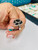 Close up view of 2.26 carat black diamond blooming flower cocktail ring worn fully on a manicured model finger
