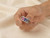 Close-up of model's fingers holding the EFFY 14K white gold rainbow sapphire ring
