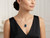 Professional lifestyle shot of model wearing the EFFY London blue topaz pendant necklace in an elegant black dress