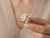 EFFY freshwater pearl and diamond statement ring held between fingers showing intricate yellow gold design