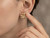 Close-up of model pointing gently near the EFFY diamond earrings worn on the ear