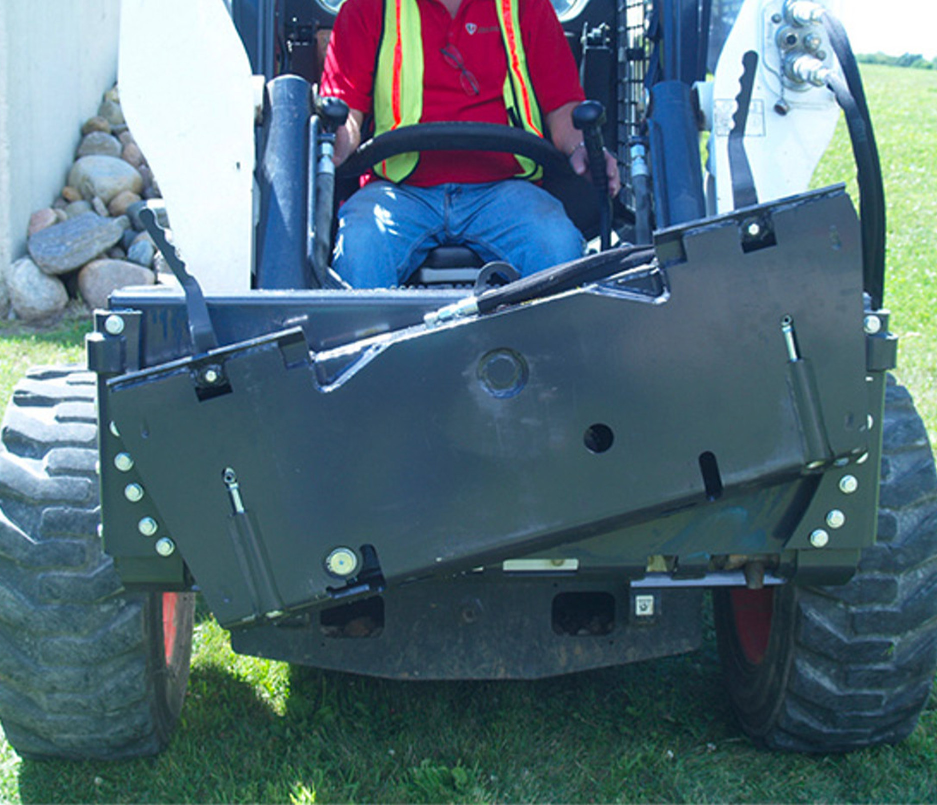 front view of the bradco power tilt tach with 3rd valve , mounted on a skid steer, tilted to the left