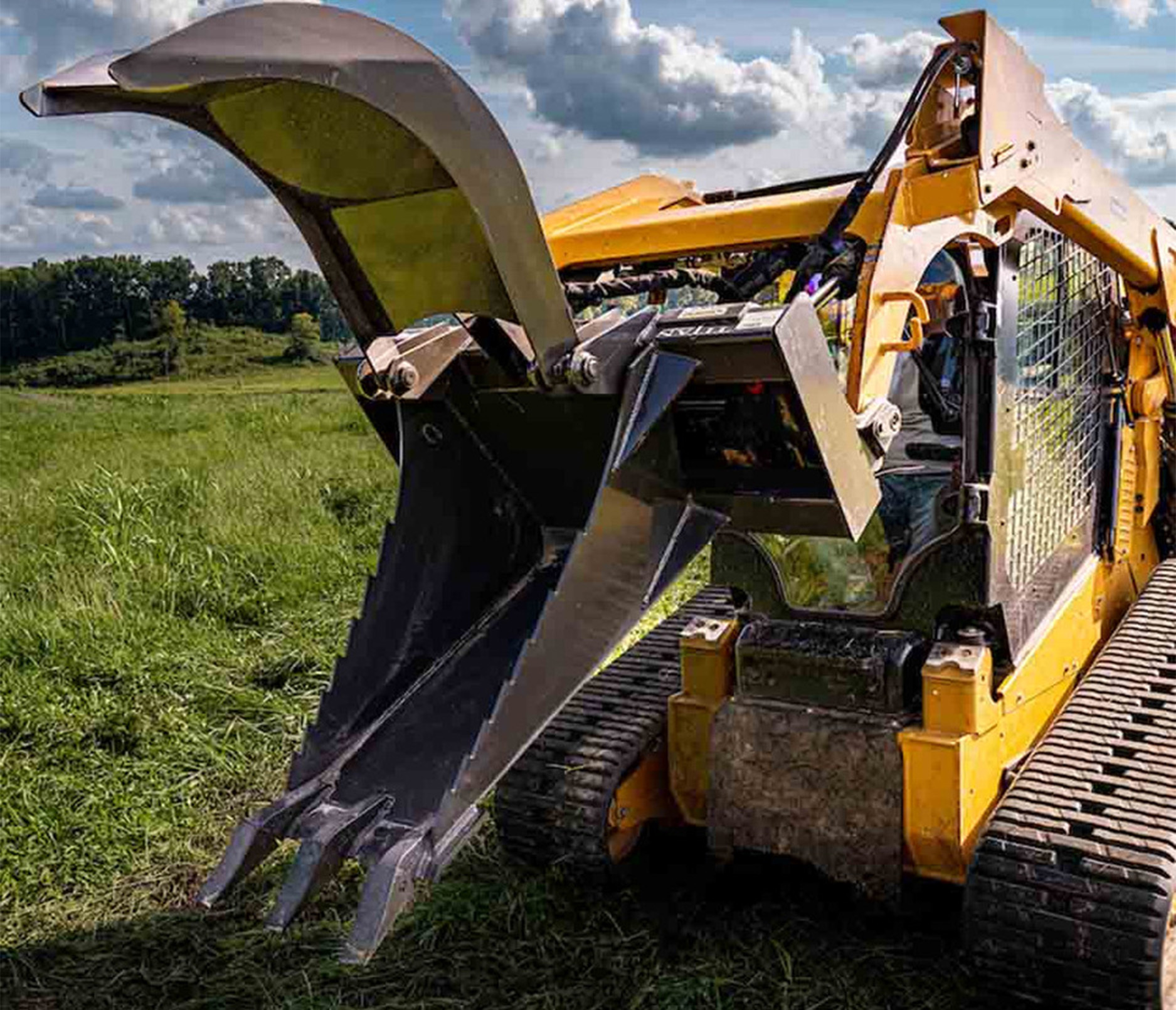 front right angled view of skid steer parked on grass with a cid stump grapple attachment on the front with the jaws open