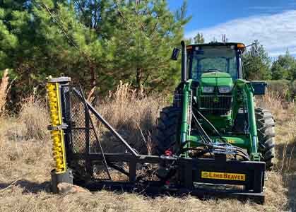 A man in a field using a side chute handle to pour concrete from the Eterra Skid Steer Mix and Go Concrete mixer into a wheelbarrow