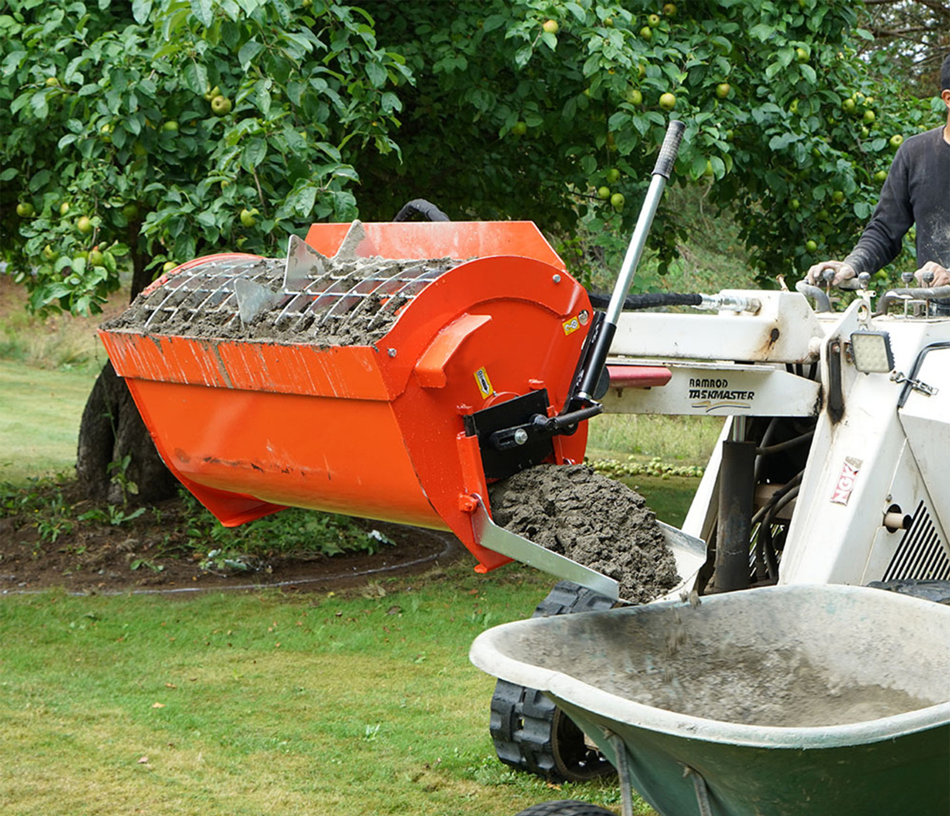 mini skid steer parked on grass with an Eterra Mini Mix & Go Concrete mixing attachment, mixing a batch of concrete