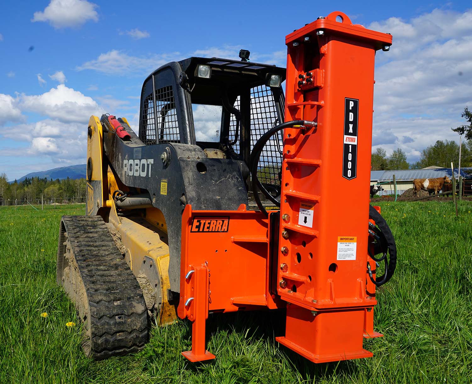 Front angled view of the Eterra PDX-1000 Post Driver attached to a skid steer parked in a field