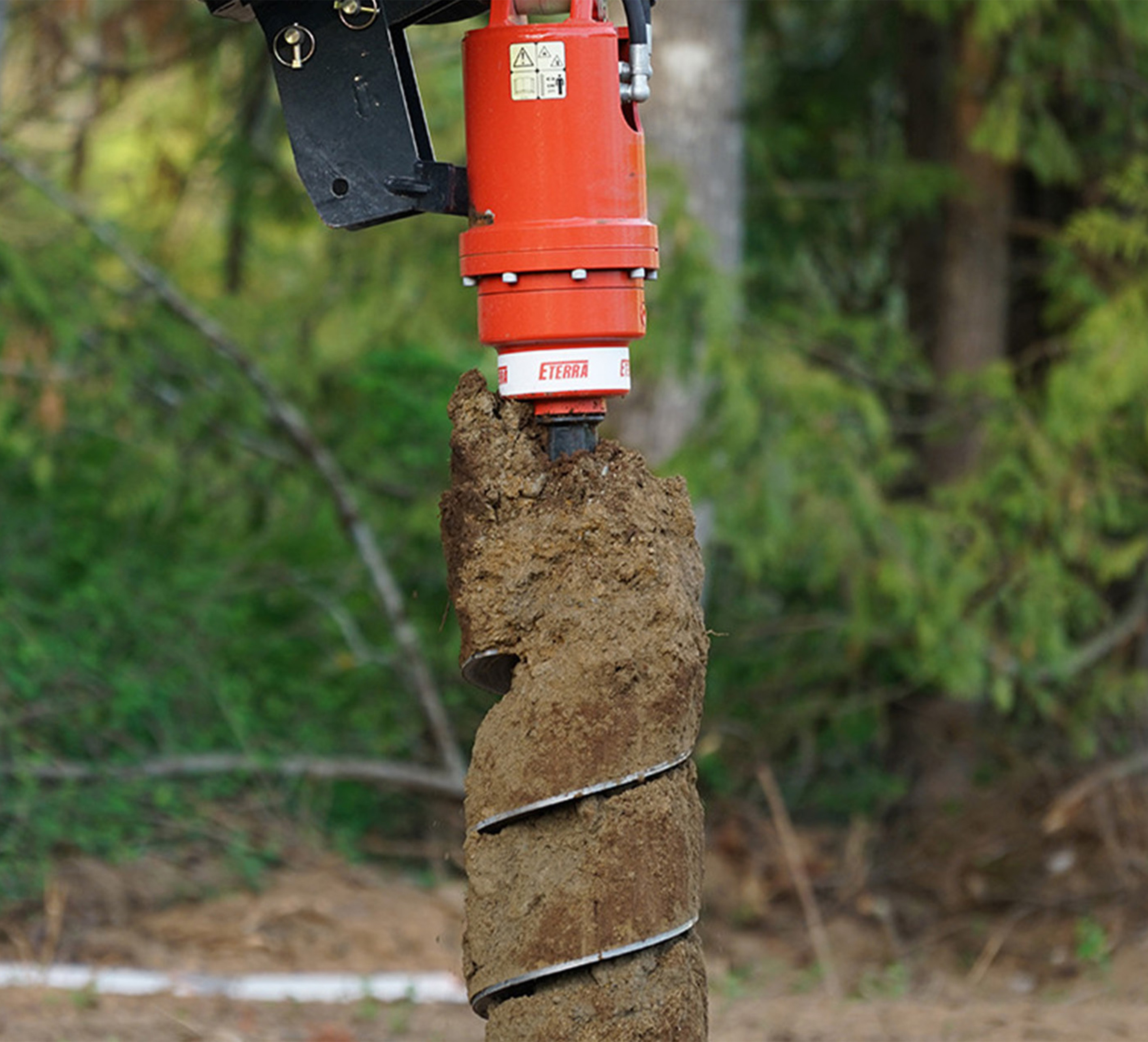 closeup shot of the eterra skid steer auger attachment pulling dirt up from the ground