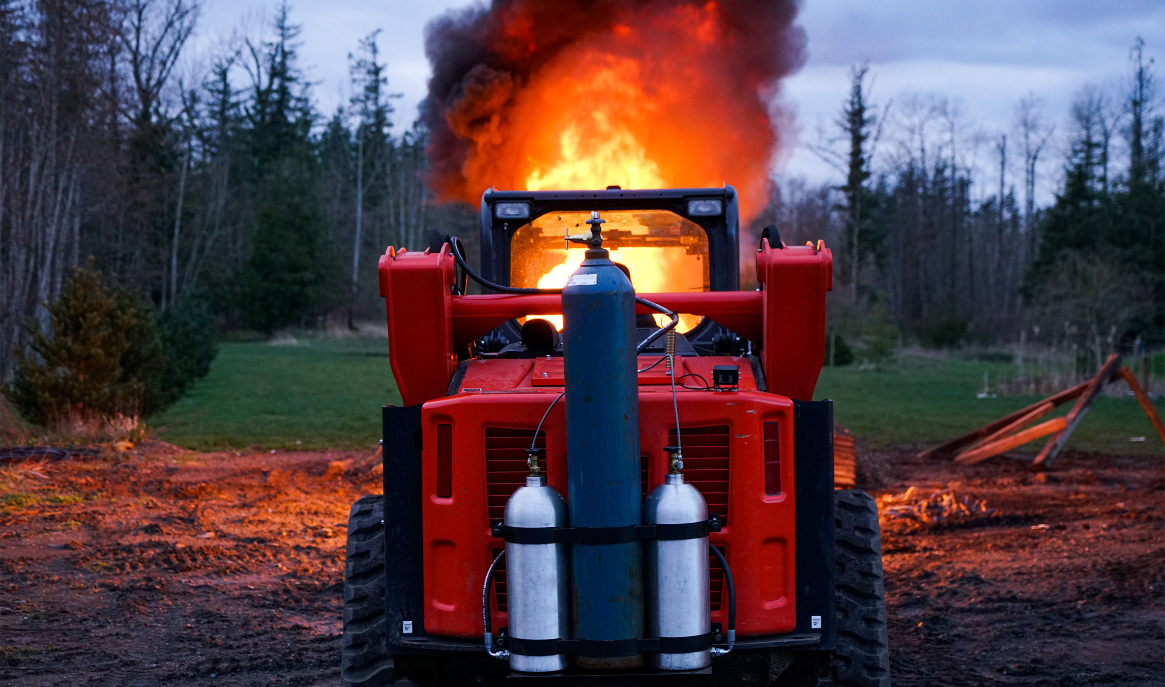 Back view of the Eterra flamethrower attached to a skid steer shooting flames out of the front