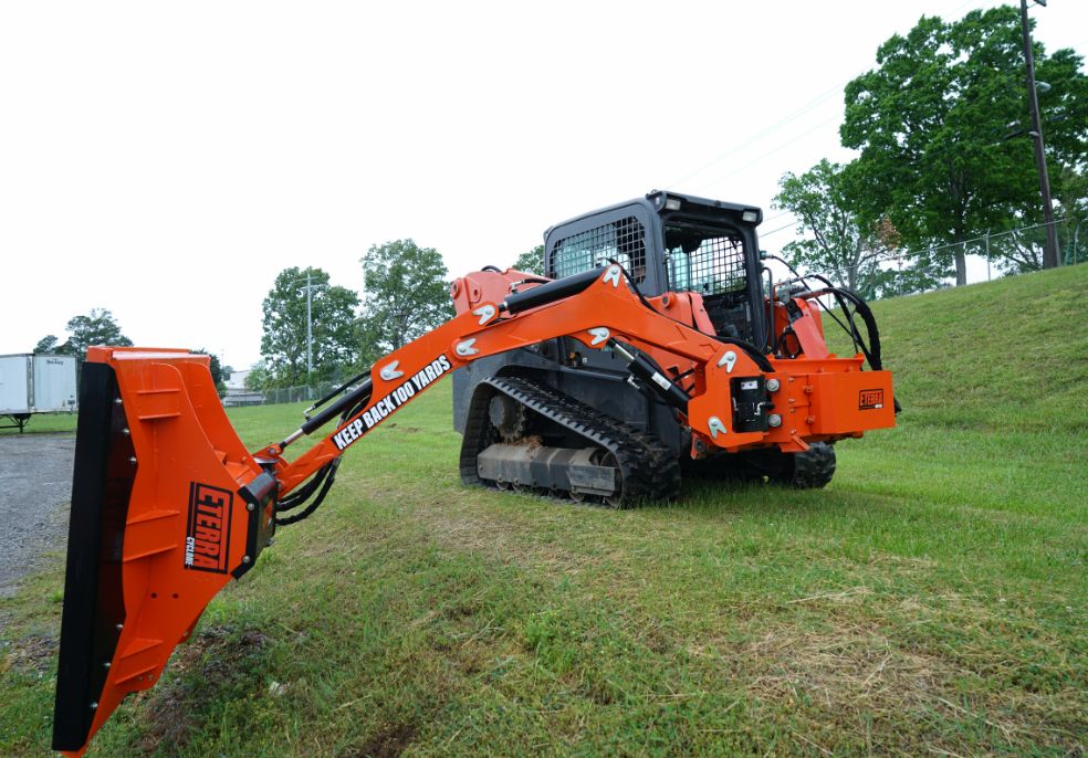 Photo of a kubota skid steer using a boom mower in a field