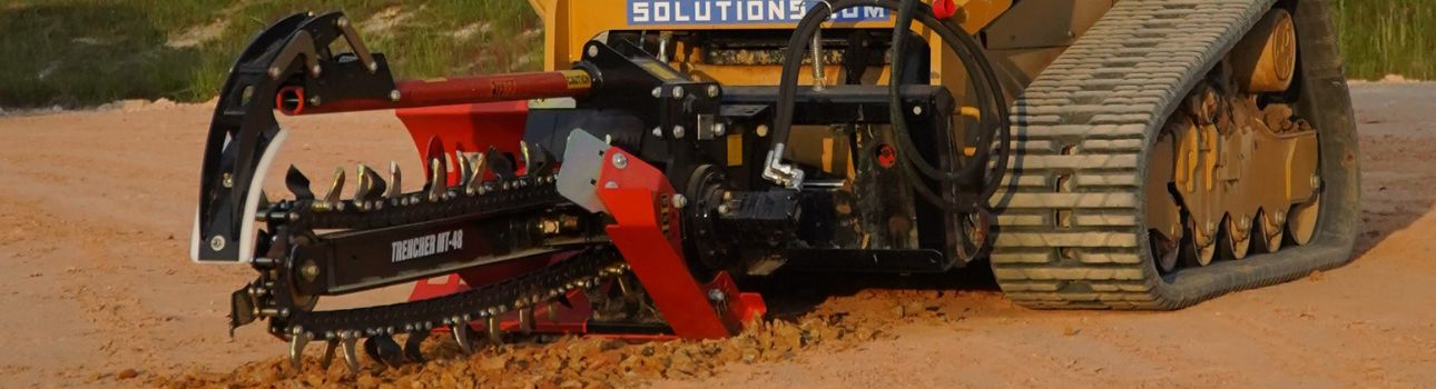 Skid Steer Trencher Attachment closeup angled view of an Eterra 4 Foot Trencher attached to a skid steer, trenching into the dirt
