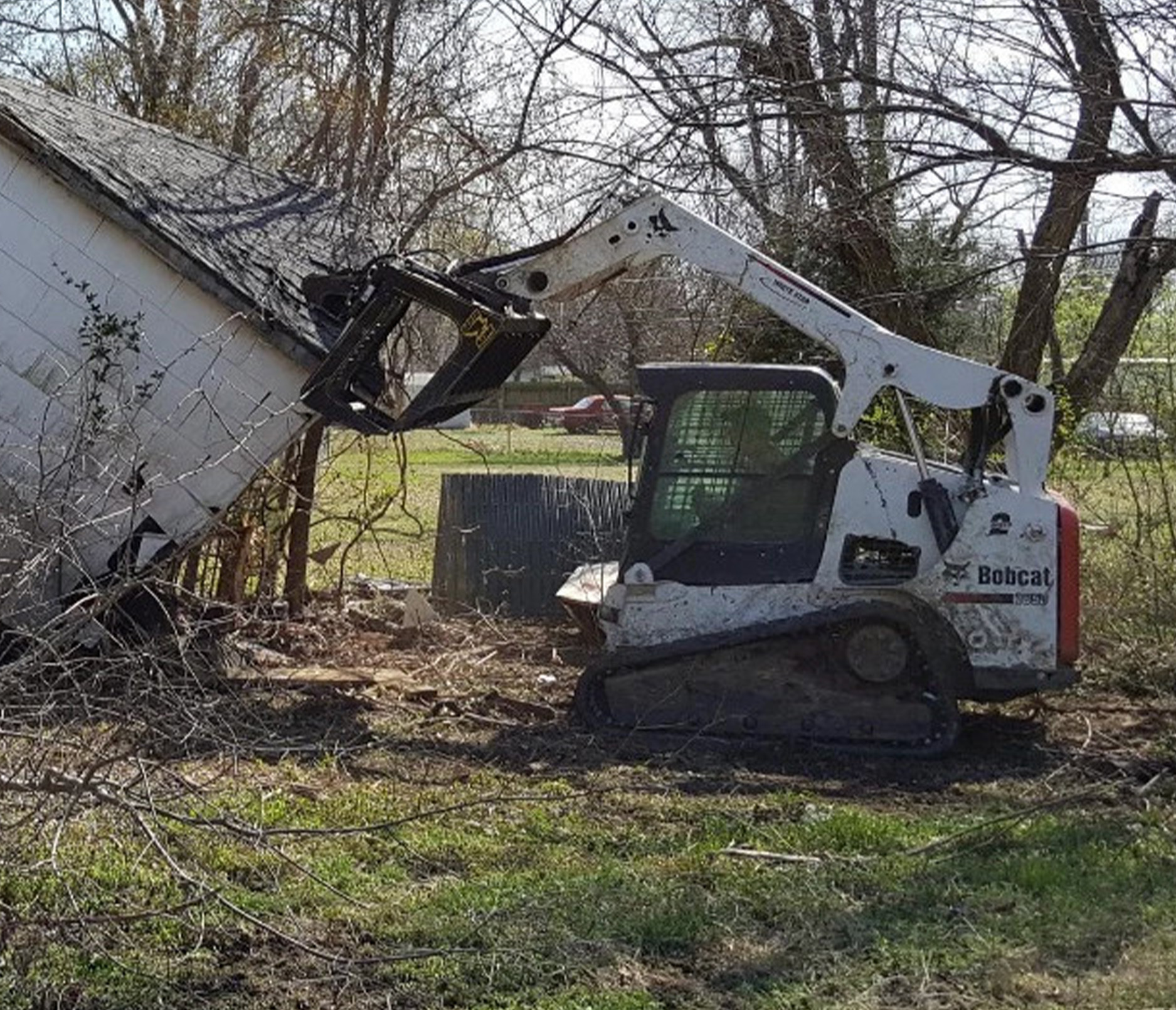 side view of a skid steer with an m&m brush hawk root grapple attachment 