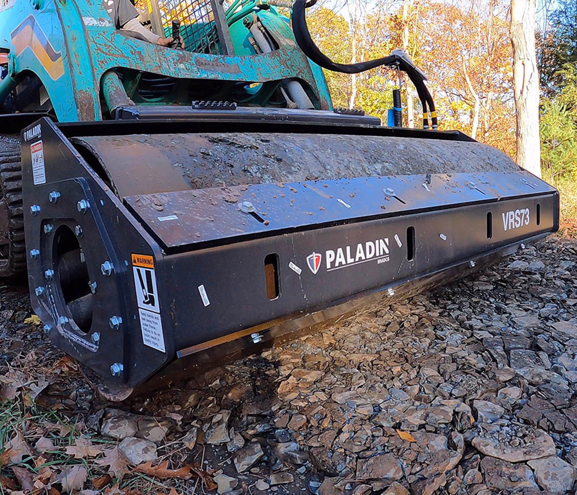 closeup left angle of the paladin vibratory roller attachment attached to a green skid steer