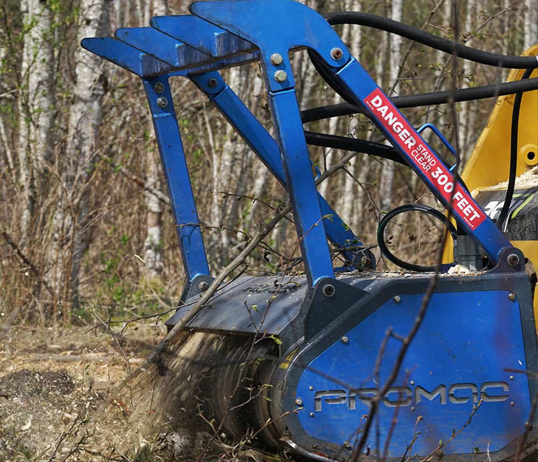 Closeup action shot of a Promac Skid Steer Forestry Mulcher Attachment mulching down a tree