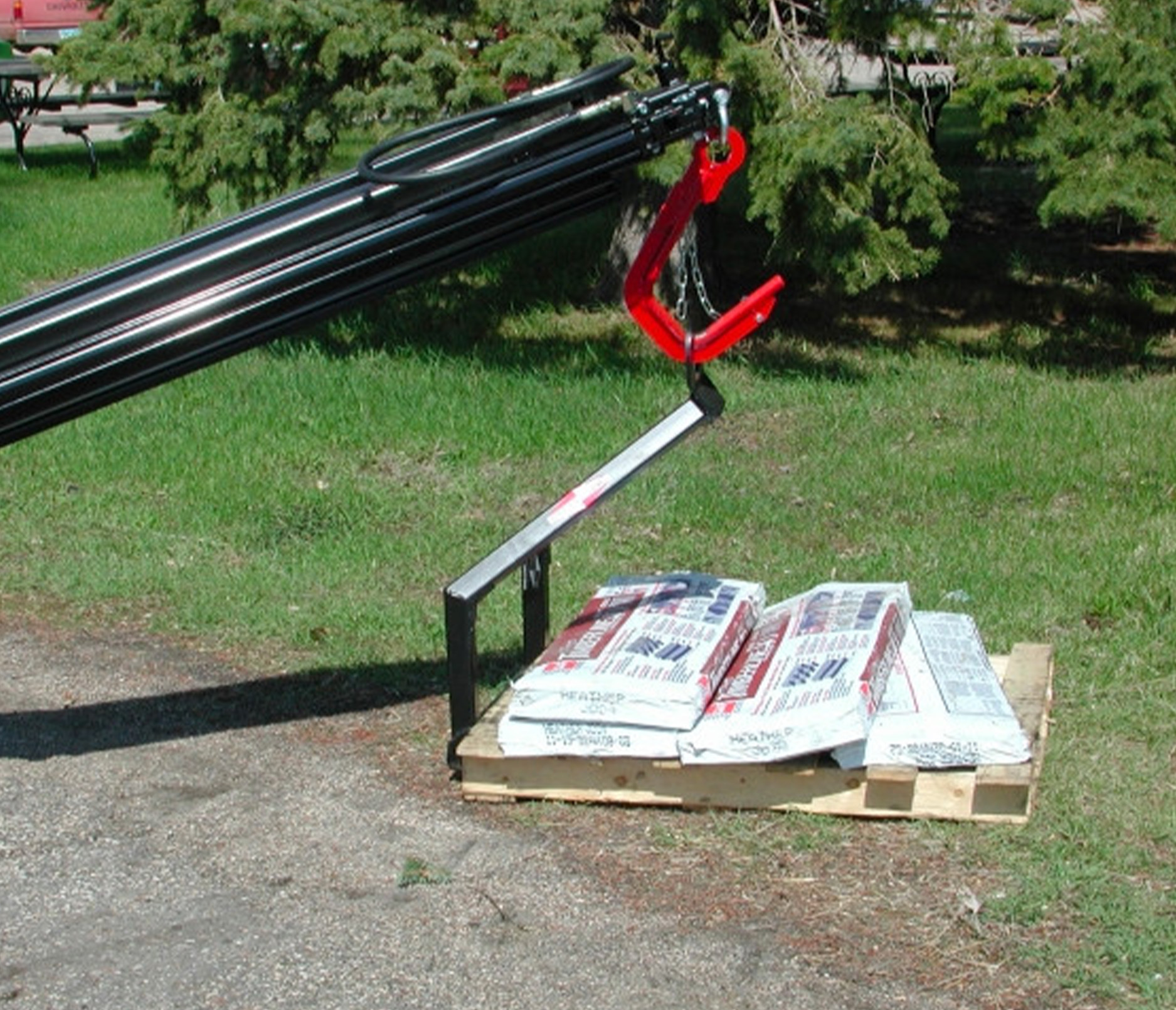 close up angle of the sheyenne skid steer tele-boom pallet carrier attachment moving a pallet of concrete mix 