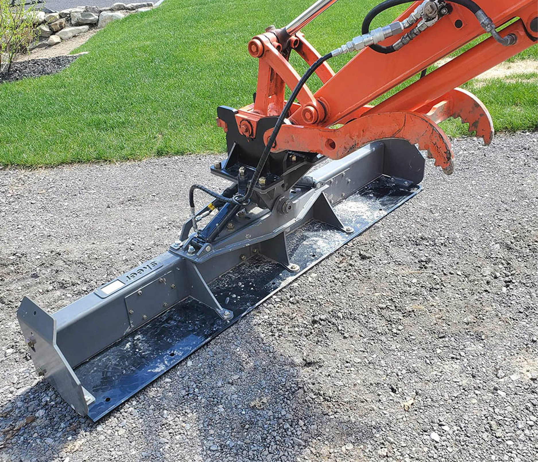 back angled view of a skeer excavator grade beam attachment on a gravel driveway positioned for grading