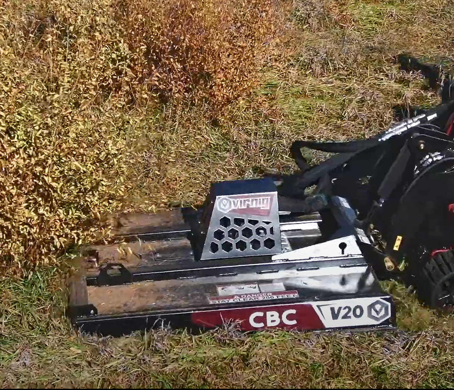 left top angled view of the virnig v20 mini skid steer closed front brush cutter attachment mowing dry grass