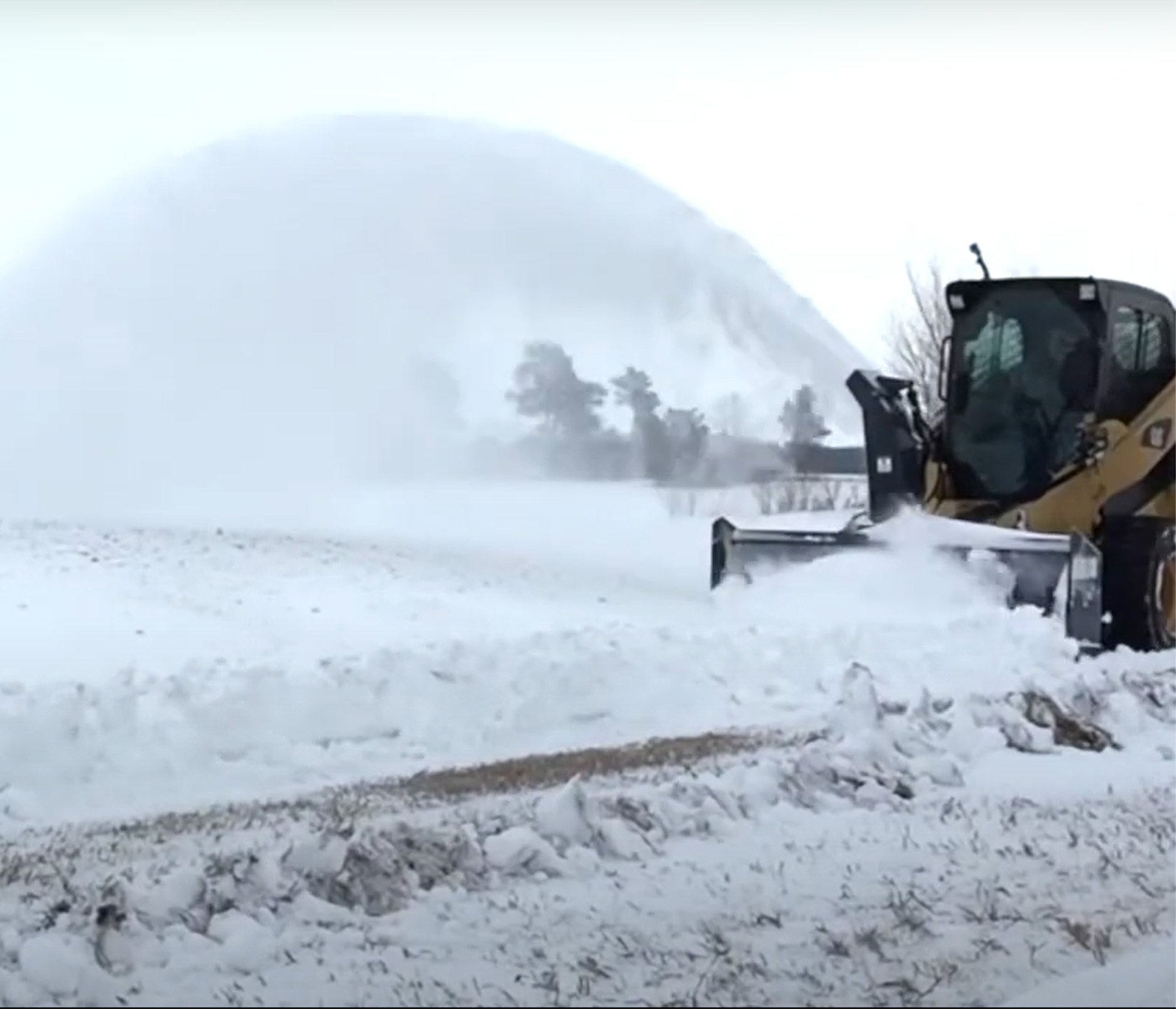 front wide angle of a skid steer blowing snow with a virnig v50 skid steer snow blower attachment