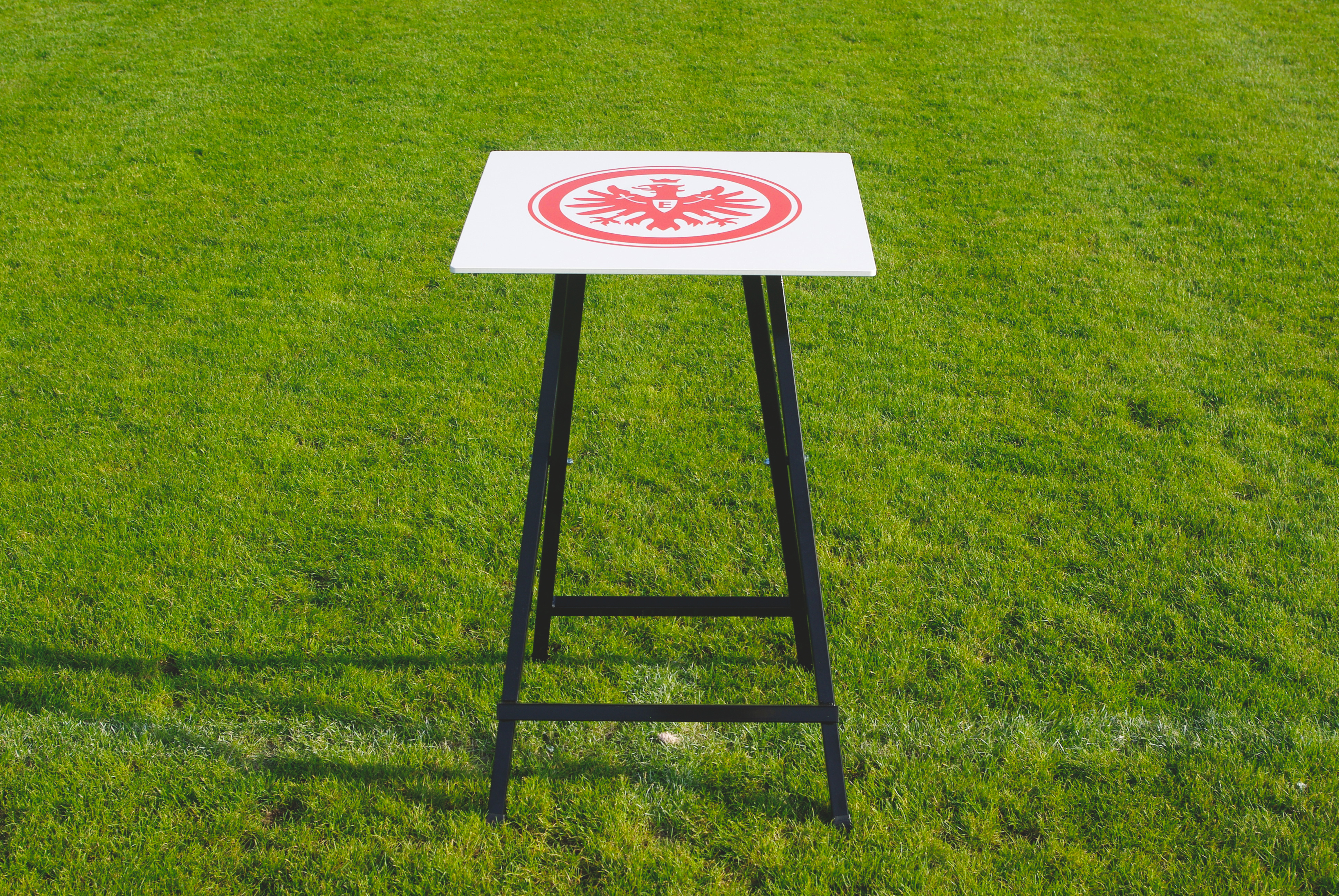 Stehtisch mit Eintracht-Frankfurt-Logo auf grünem Rasen